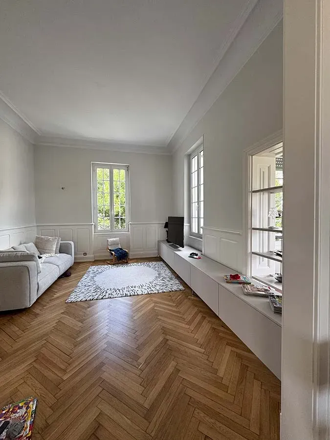 Vue en longueur d'un salon avec tapis et meuble télé